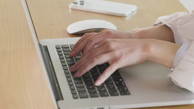 Close-up of woman's hands typing on laptop keyboard