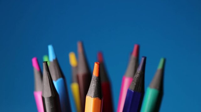 Stationery supplies, colored pencils for drawing rotating on a blue background