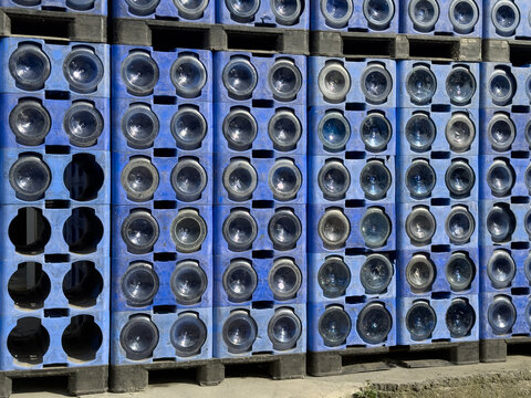 View of stacked blue plastic crates filled with large water bottles on wooden pallets under bright daylight Sariyer, Istanbul, Turkiye.