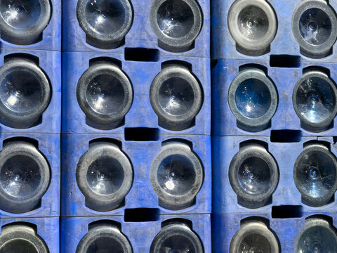 View of empty glass bottles stacked in blue plastic crates under bright sunlight in Sariyer, Istanbul, Turkey.