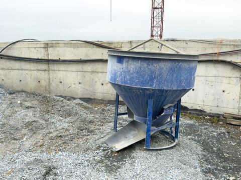 View of a blue concrete bucket on a construction site with a concrete wall and a crane tower in the background Sariyer, Istanbul, Turkiye.