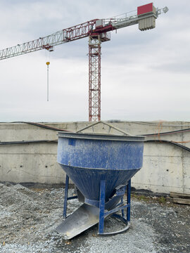 View of a blue concrete bucket on a construction site with a tall tower crane and a concrete wall under a cloudy sky Sariyer, Istanbul, Turkiye.