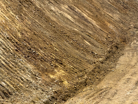 View of an excavated dirt slope with visible soil layers and heavy machinery tire tracks at a construction site in Sariyer, Istanbul, Turkiye.