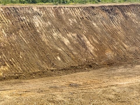 View of an excavated dirt wall at a construction site with visible soil layers and greenery on top in Sariyer, Istanbul, Turkiye.