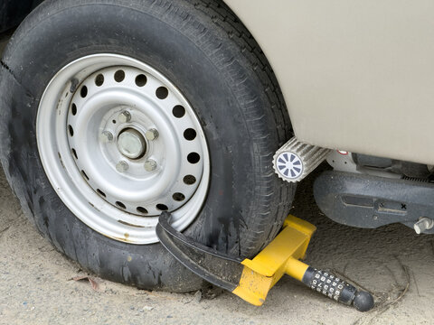 View of a yellow wheel clamp security lock attached to a vehicle tire with a motor mover roller in Sariyer, Istanbul, Turkiye.