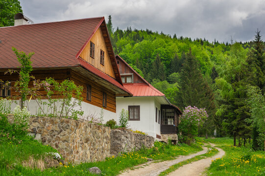 View of the former charcoal burners' settlement Bukovec featuring traditional wooden houses and stone walls along a dirt path in Motycky, Banskobystricky kraj, Slovakia.