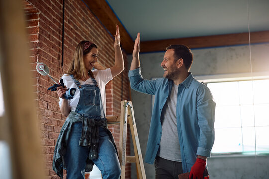 Happy couple giving high-five after successful home renovation.