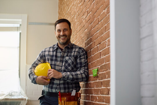 Happy building contractor working on home remodeling project looking at camera.