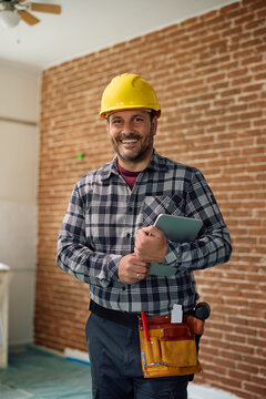 Happy professional builder working on site and looking at camera.