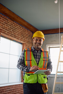 Happy construction site foreman working on touchpad and looking at camera.