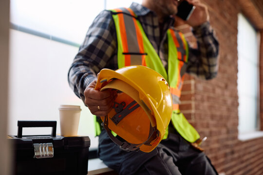 Close up manual worker with yellow hardhat at construction site.