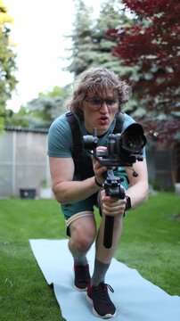 Vertical screen Videographer practices smooth walking technique with camera gimbal improving stabilization control balance and professional filming movement outdoors
