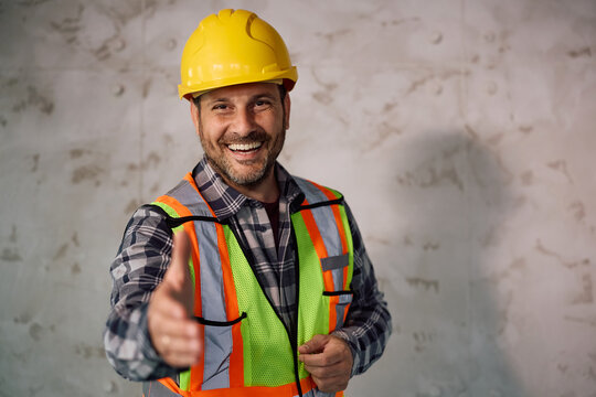 Happy building contractor reaching out for handshake and looking at camera.