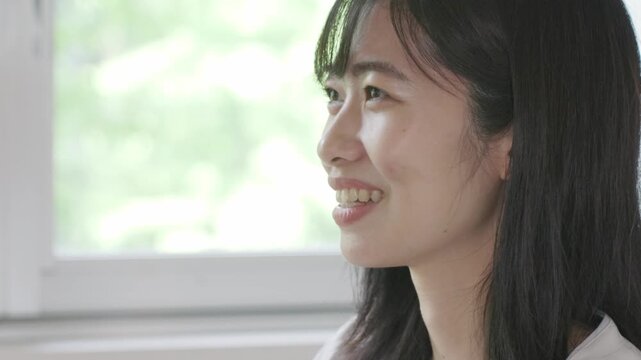 Young Asian woman smiling and talking while using laptop