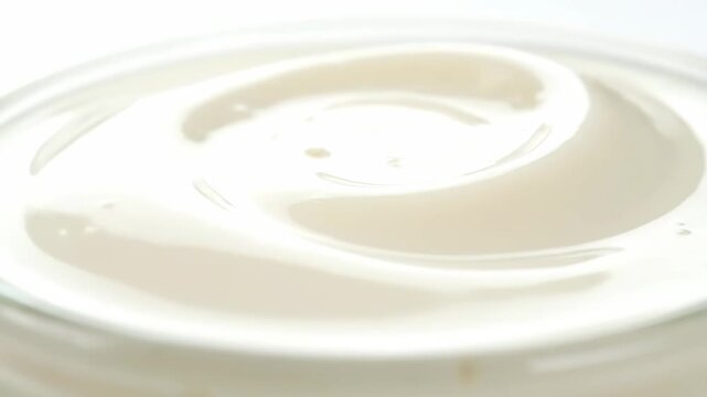 Close-up macro shot of thick creamy white yogurt or whipped cream with a smooth swirl texture on a white background