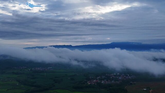 Multiple Cloud Layers Over Karst Peaks with Wind Turbines, Rural Fields and Houses Seen Through Gaps