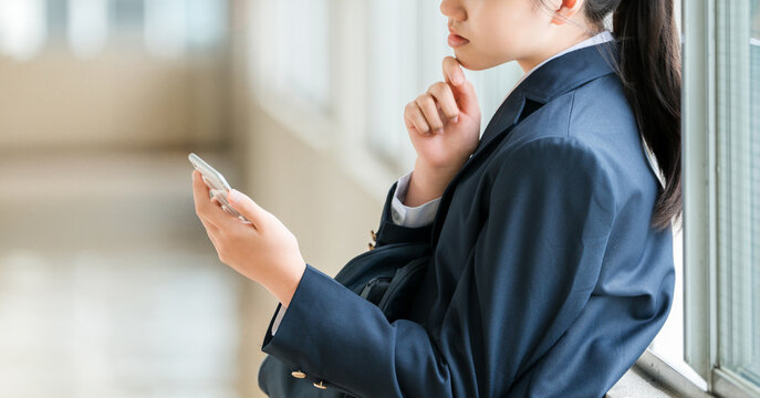 Smiling elementary, middle, and high school girls using smartphones in the school hallway (crime prevention, safety, security)