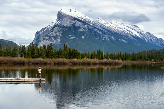 Woman on a dock admiring a snow capped mountain view