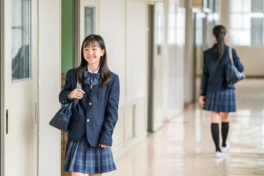 Elementary, middle, and high school girls in uniform walking down a school corridor.