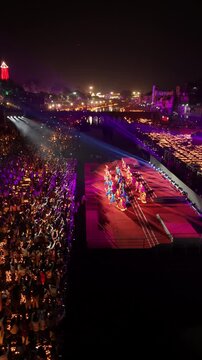 Ayodhya, India - 30 October 2024: Aerial view of performers on a stage during the Deepotsav festival with crowds and thousands of oil lamps along the Saryu river at night.