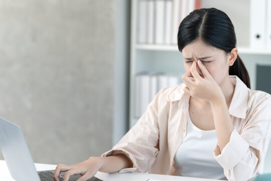 Eye problems, Asian women open eyes due to eye irritation, eye rubbing, dry, eye pain after work, migraine, headache, blurred vision, photophobia, working in the dark, blue light from computer screens