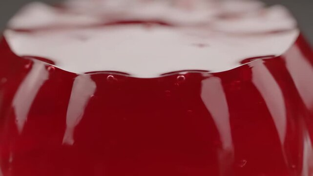 Abstract macro close-up of vibrant red shiny gelatin dessert texture. delicious sweet jelly pudding background.