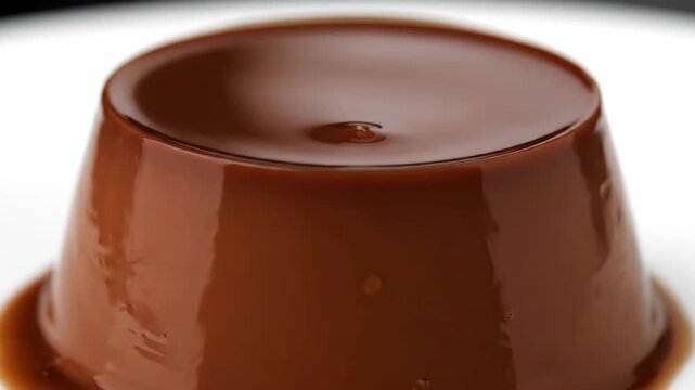 Decadent close-up of rich, glossy chocolate flan (cr&egrave;me caramel) dessert, perfectly molded and set against a bright white background for food photography.