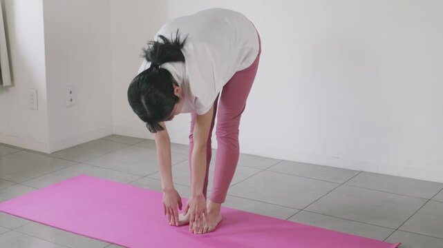 Woman doing forward bend stretch on yoga mat