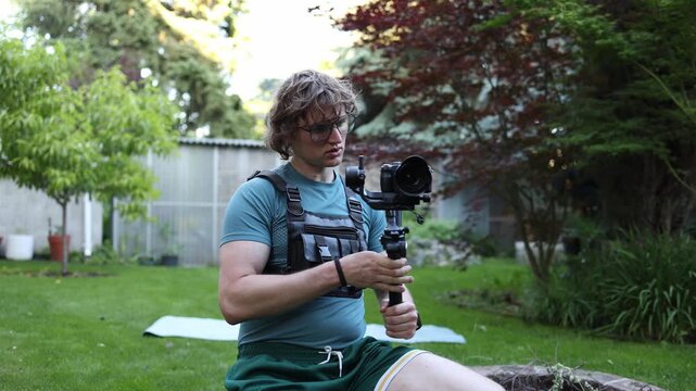 Professional videographer films outdoor scenes with a camera gimbal capturing stable cinematic footage in a green garden surrounded by nature