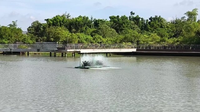 A paddlewheel aerator floating on the water, splashing water into the air to increase oxygen levels.
