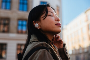 Woman listening with earbuds while standing in city © Jacob Lund