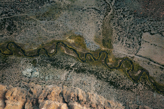 Aerial view of the winding river of Canon de la Anaconda flowing through the arid desert landscape with rocky cliffs in Villa Alota, Potosi Department, Bolivia.