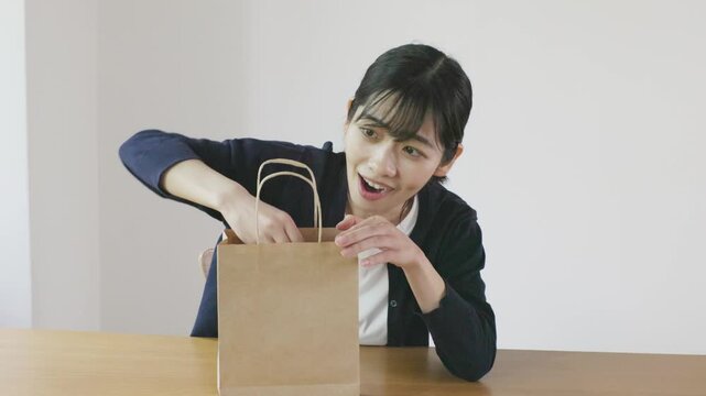 Young Asian woman smiling while taking heart shaped capsule out of paper bag