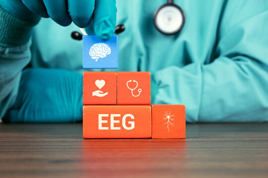 Concept of cognitive testing, neurological assessment, and early detection of brain disorders. EEG. The doctor's hand arranges wooden cubes with brain icons.