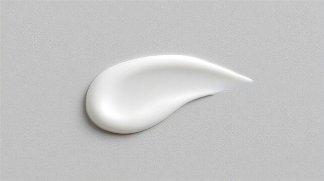 A light white serum is shown spread out on a plain light grey background