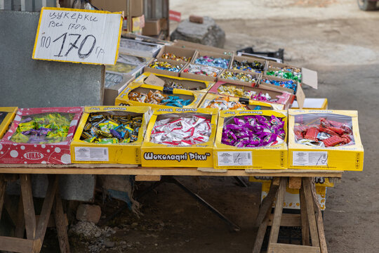 Horodok, Ukraine - March 25, 2026: Lukas chocolate candies displayed in open cardboard boxes on a wooden outdoor market stall table for retail sale to local customers in street