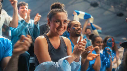 Obraz premium Portrait of a Smiling White Female Spectator Applauding During a Soccer Football Championship Match in a Stadium, Excited Diverse Crowd of Happy Fans Cheering and Celebrating a Victory at a Game.