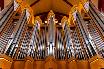 Obraz premium Majestic organ pipes rise toward the ceiling in a breathtaking cathedral setting during a serene afternoon service