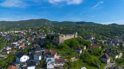 Obraz premium Aerial view of the historical medieval fortress walls surrounded by houses and green hills in Jajce