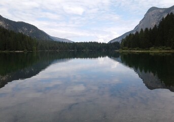 Fototapeta premium Calm Lake Reflecting Majestic Mountains and Forest