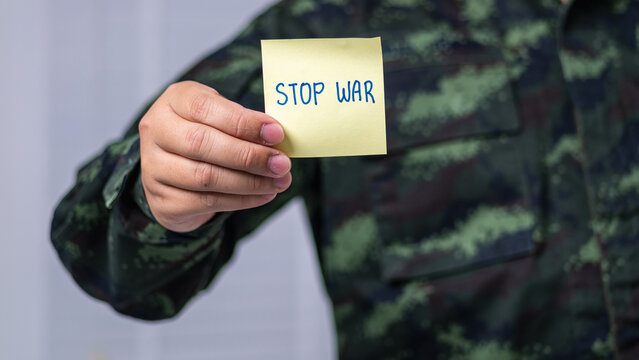 Close-up of a soldier in uniform holding a Stop War note during a peaceful protest