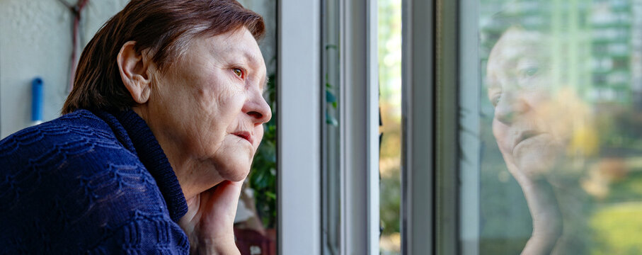 Portrait of a Sad Elderly Woman Looking Out the Window at Home