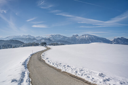 Beautiful Allgaeu Winter Panorama of Breitenberg and Pfrontener Berge with Winding Road, Scenic Snowy Alpine Landscape with Mountain Range at Sunny Day, Majestic Countryside Background
