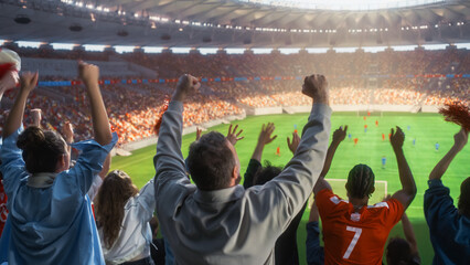 Rear Shot of Diverse Excited Soccer Fans Throwing Hands and Fists Skyward to Cheer Their Team as Footballers Battle on the Pitch, Happy Supporters Celebrating During a Championship Match in a Stadium. © Gorodenkoff