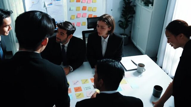 Top down aerial view of smart business man join meeting and present financial plan while diverse business people discuss and brainstorm marketing idea by using sticky notes at conference. Directorate.