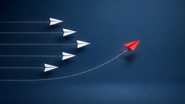 Red paper airplane changing direction from white airplanes on dark blue background, symbolizing leadership, disruptive innovation and strategic vision