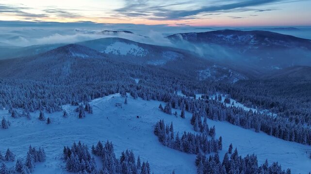 Drone orbit view of twilight mountain landscape with rolling fog and hiker silhouettes