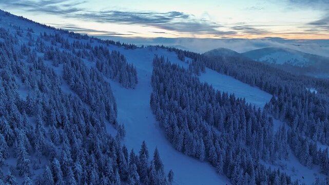 Aerial forward flight over snow heavy slopes of Pilsko mountain at twilight