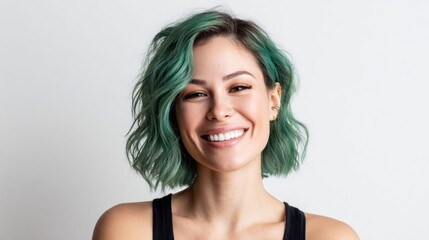 Naklejka premium Young woman with vibrant teal hair smiling broadly against a clean white background