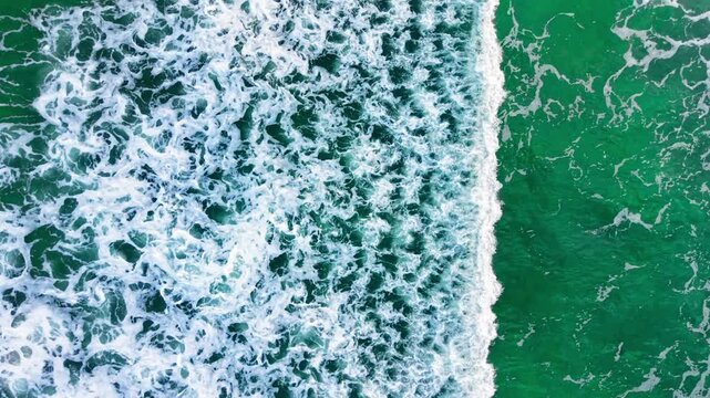Texture of vibrant emerald surf and white marine bubbles ripple pattern. Emerald sea water with dense white foam pattern.